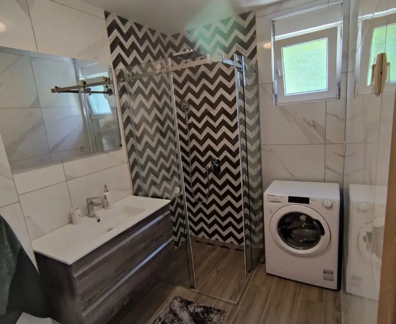 Modernly equipped bathroom with a shower cabin and a washing machine.