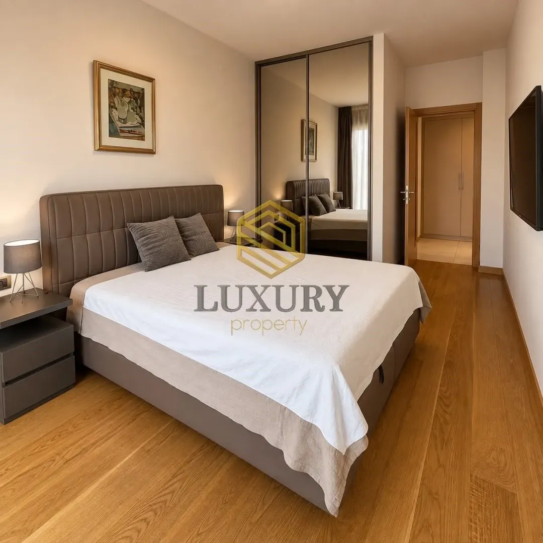Modern bedroom with a double bed, mirrored wardrobe, and wooden flooring.