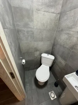 Small bathroom with grey tiles, toilet, and sink. - image 6