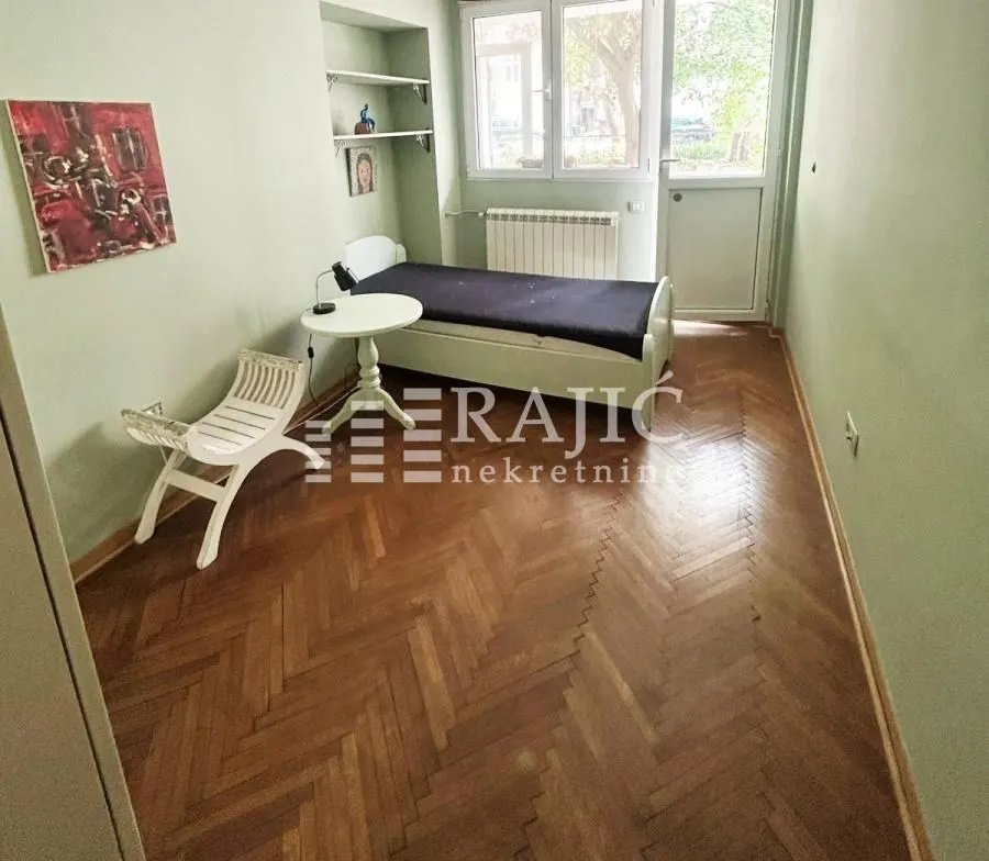 Smaller bedroom with a bed and parquet flooring.