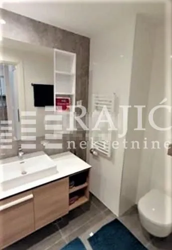 Modern equipped bathroom with a washbasin, mirror, and toilet bowl.