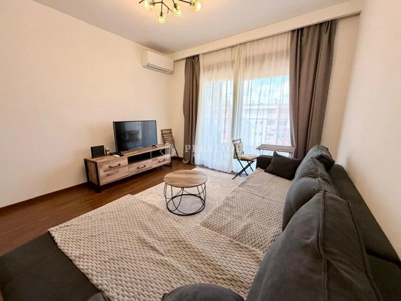 Furnished living room with a sectional sofa, TV, and balcony access.