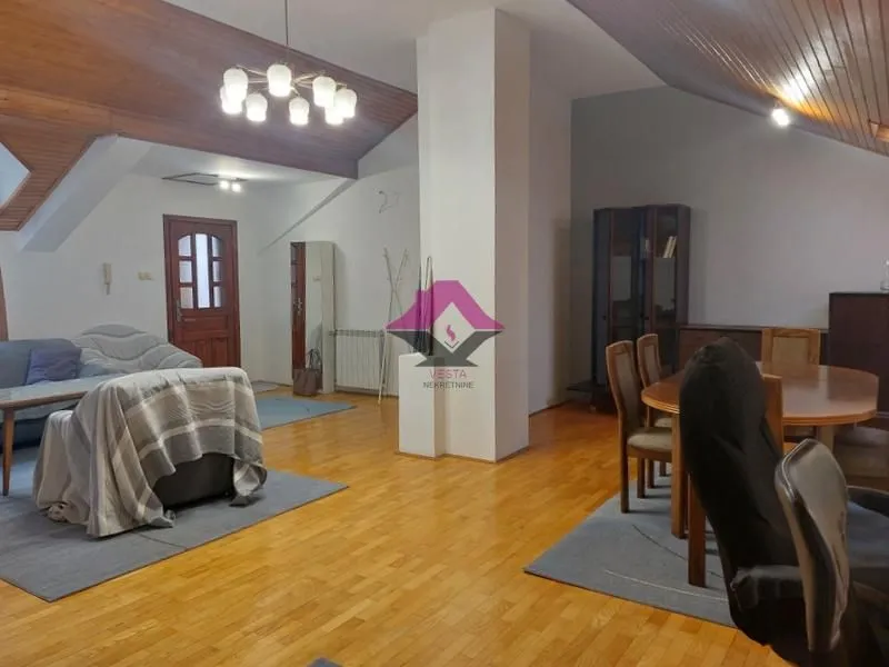 Prostrani dnevni boravak sa trpezarijom i drvenim plafonom.