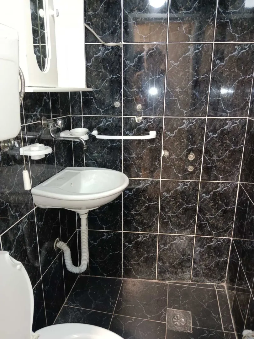 Simple bathroom with dark tiles and a white sink.