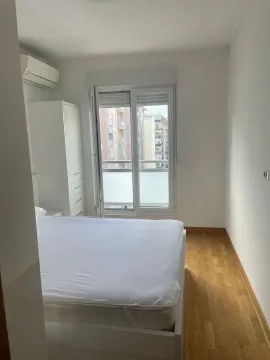 Bright bedroom with a double bed, white wardrobe, and balcony doors. - image 6