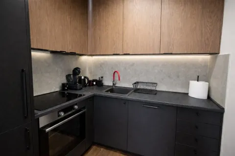 Modern kitchen with black units and wooden wall cabinets. - image 9