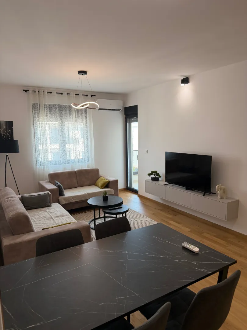 Modern living room with a sofa, TV, and dining table.