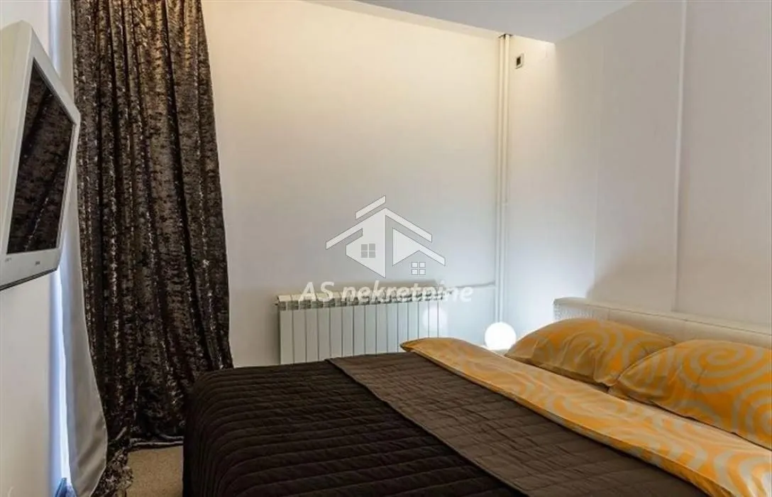 Bedroom with a large double bed and dark curtains.