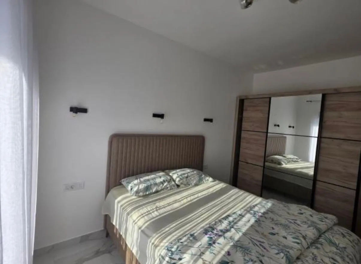 Moderna spavaća soba sa bračnim krevetom i velikim ormarom sa ogledalom.