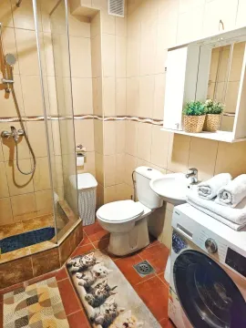 Compact bathroom with a shower cabin, toilet, sink, and washing machine. - image 17