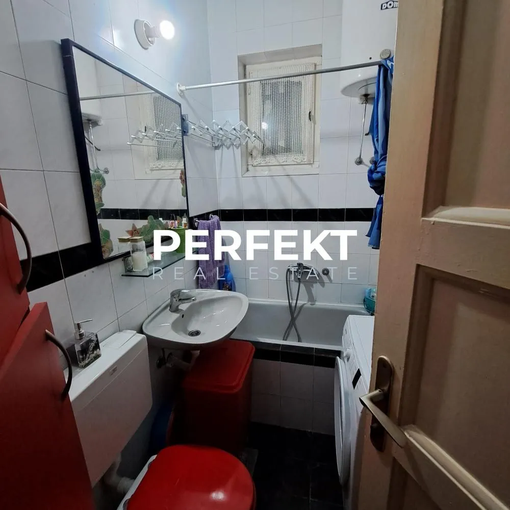 Manje kupatilo sa kadom, umivaonikom, wc šoljom i veš mašinom.