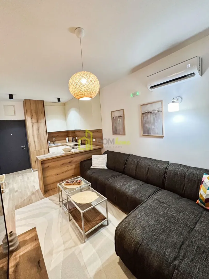 Living room with sofa, coffee tables, and an open layout towards the kitchen.