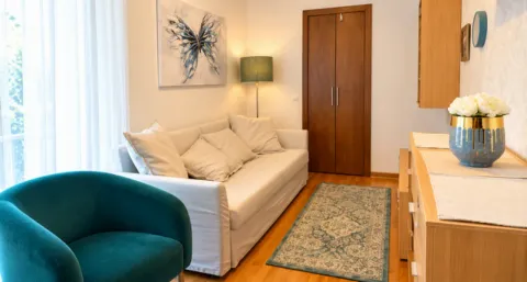 Living room with a light sofa, green armchair, and wooden flooring. - image 11