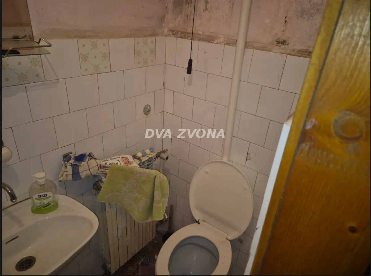 Starije kupatilo sa umivaonikom i wc šoljom.