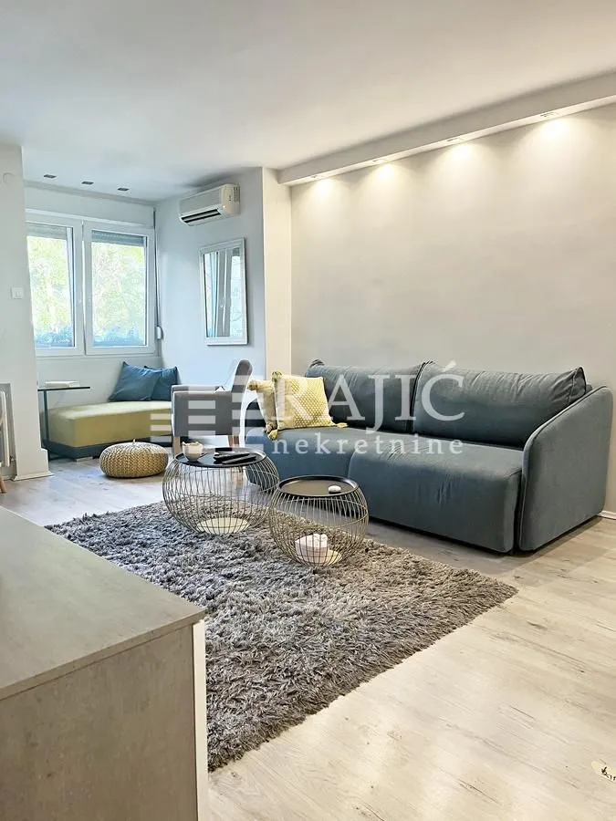 Modern living room with a sofa, coffee tables, and a rug.