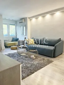 Modern living room with a sofa, coffee tables, and a rug. - image 2