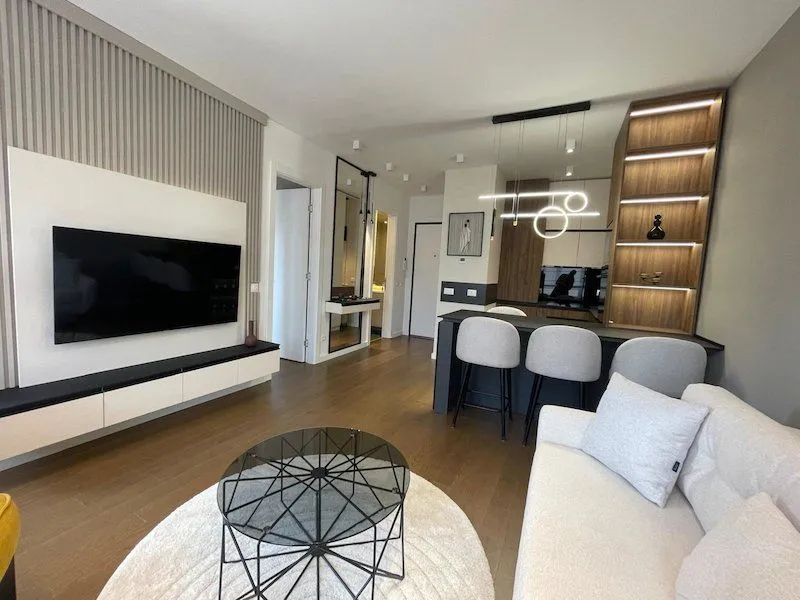 Modern living room with a sofa, television, and a dining area in the background.