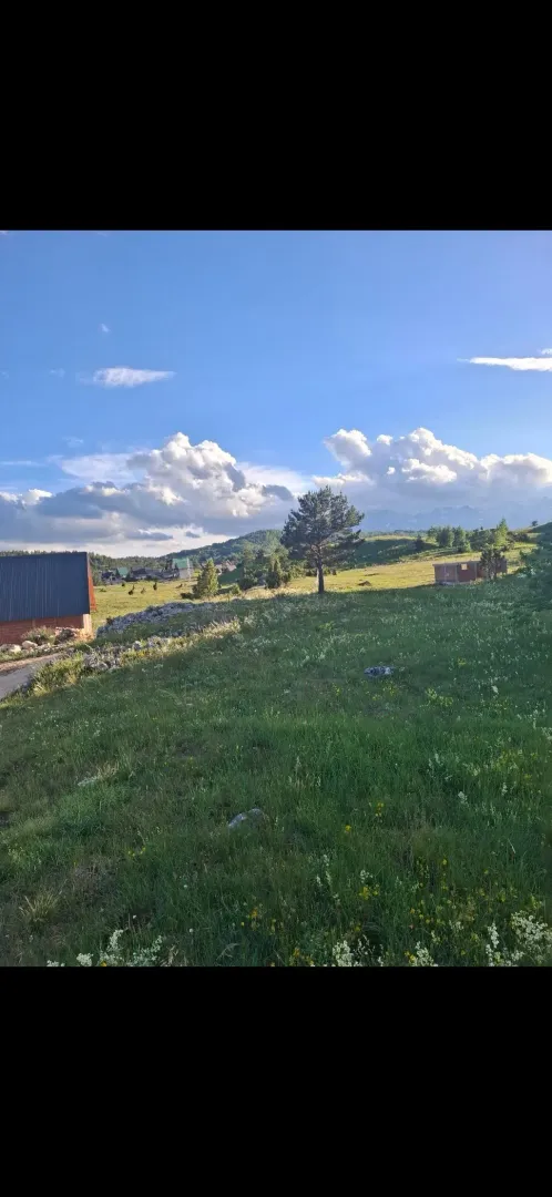 Pogled na prostrano travnato zemljište i okolnu prirodu.