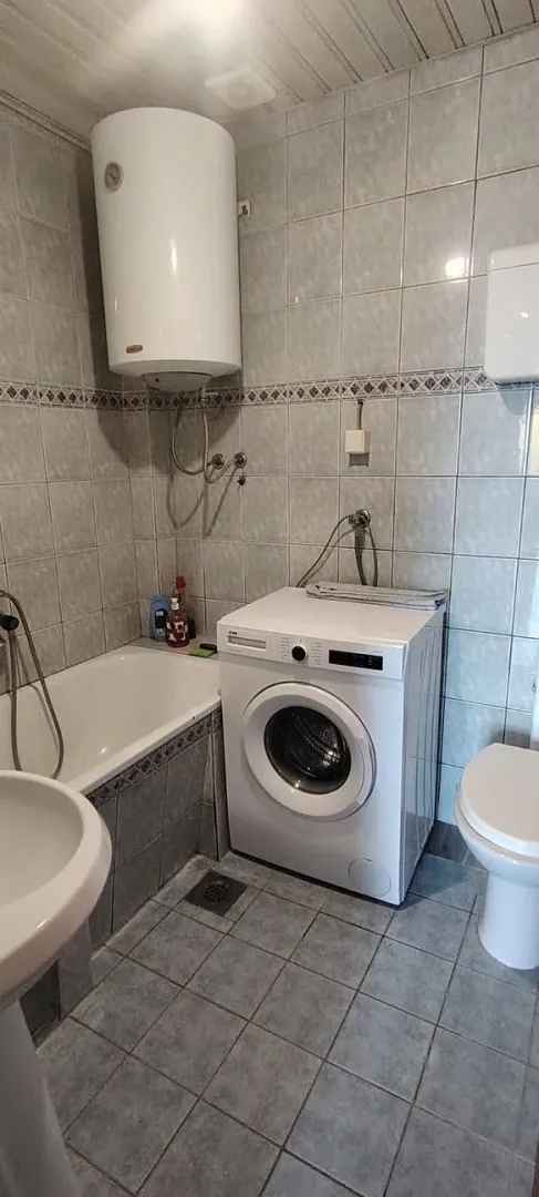 Small bathroom with a bathtub, washing machine, and water heater.
