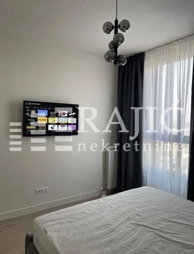 Furnished bedroom with a double bed and wall-mounted television.
