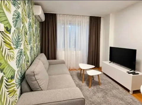 Living room with a sofa, TV, and botanical pattern wallpaper. - image 2