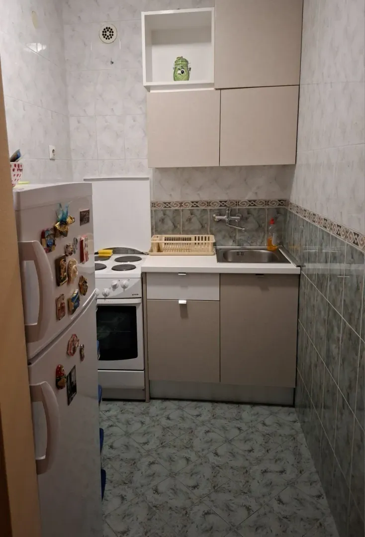 A small functional kitchen with light cabinets, a stove, and a refrigerator.