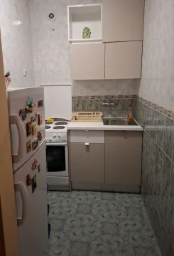 A small functional kitchen with light cabinets, a stove, and a refrigerator. - image 6