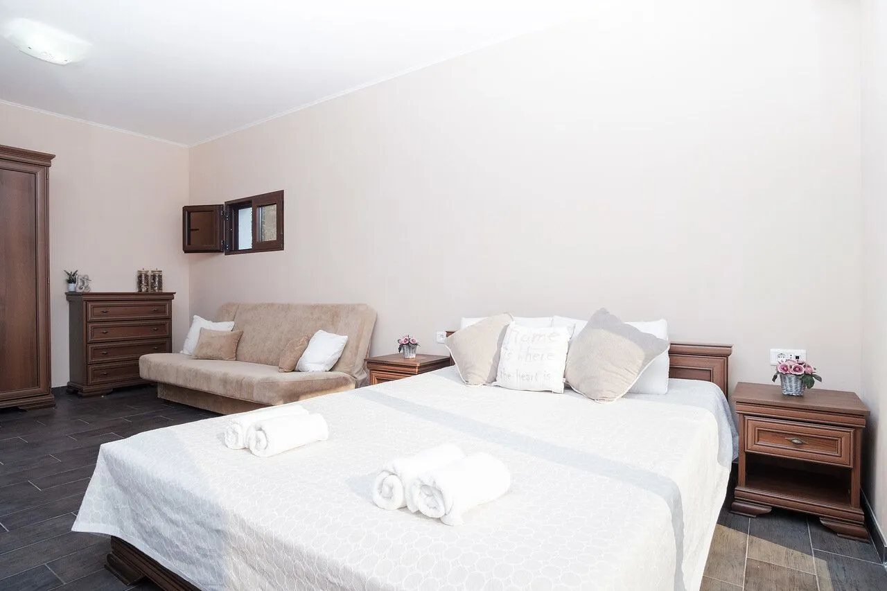 Furnished bedroom with a double bed, sofa, and chest of drawers.