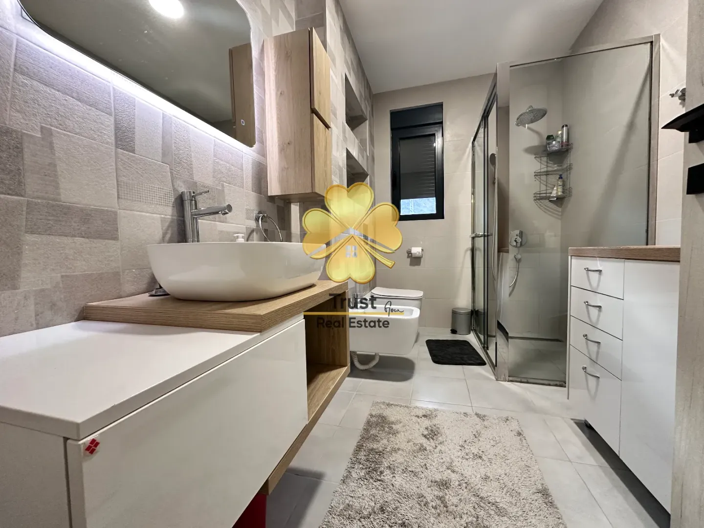 Modern bathroom with a washbasin, walk-in shower, and sanitary fixtures.