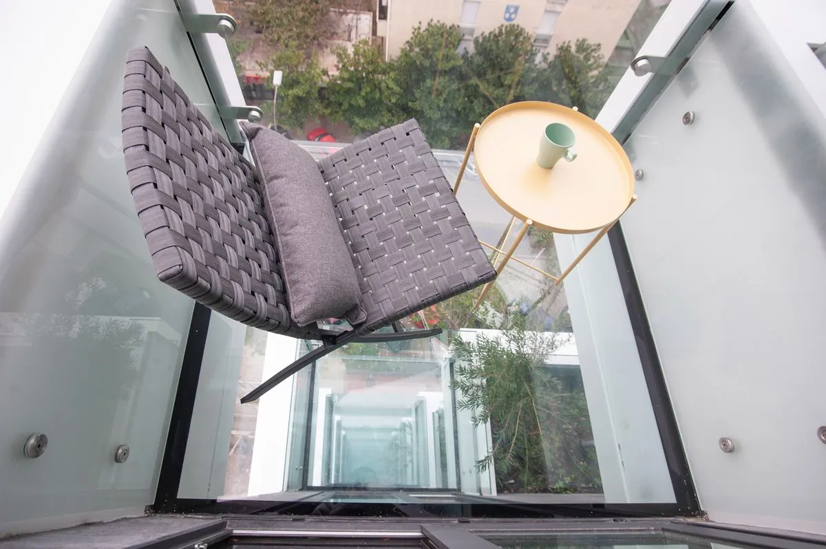 Modern and bright balcony with a comfortable armchair and a small table.