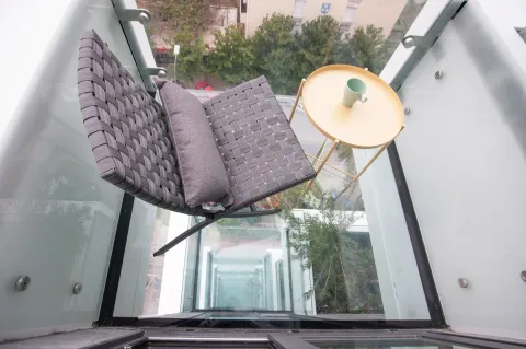 Modern and bright balcony with a comfortable armchair and a small table. - image 6