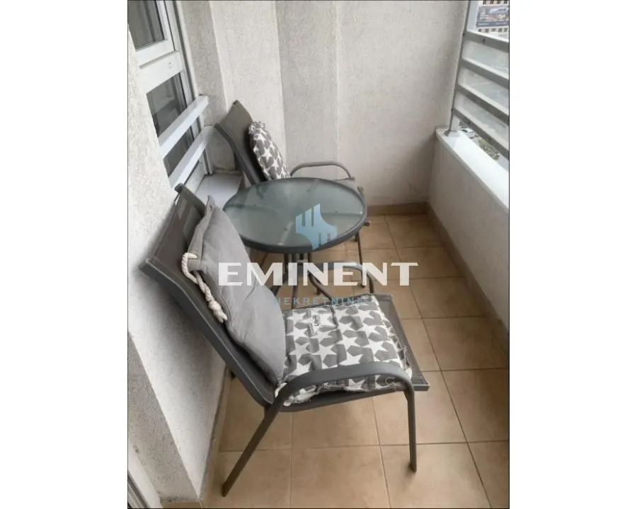 Manji namešten balkon sa stolom i dve stolice.