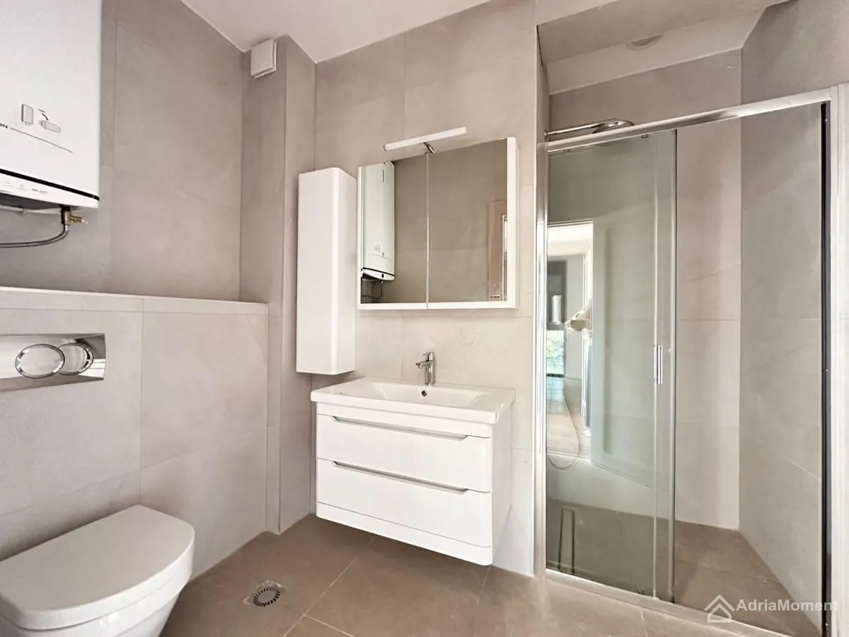 Savremeno opremljeno kupatilo sa tuš kabinom, umivaonikom i wc šoljom.