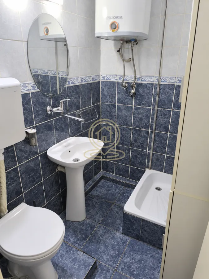Manje kupatilo sa pločicama u plavim tonovima, umivaonikom, WC šoljom i tuš kadom.