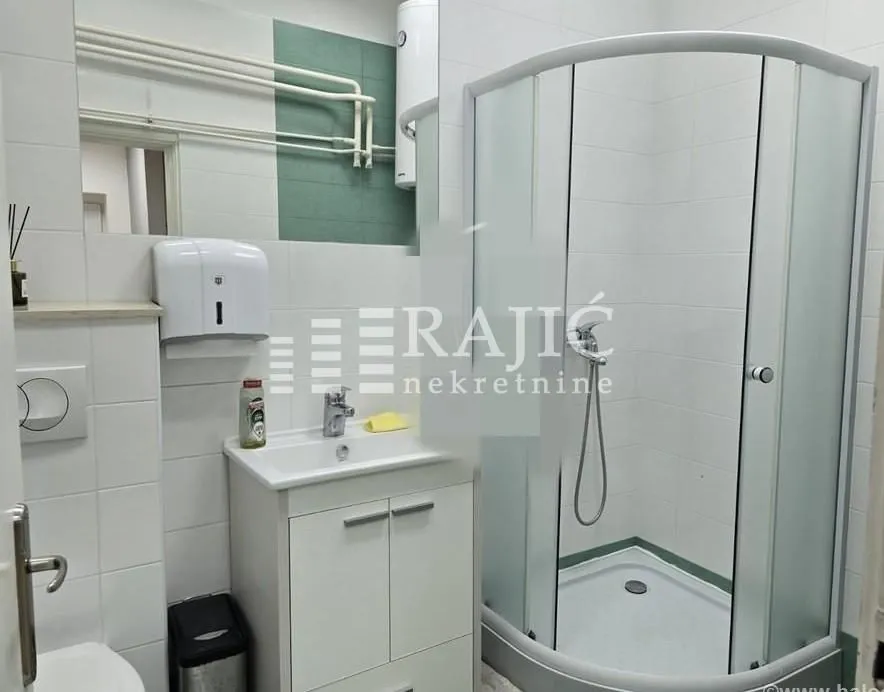 Small bathroom with a shower cabin, washbasin, and white tiles.