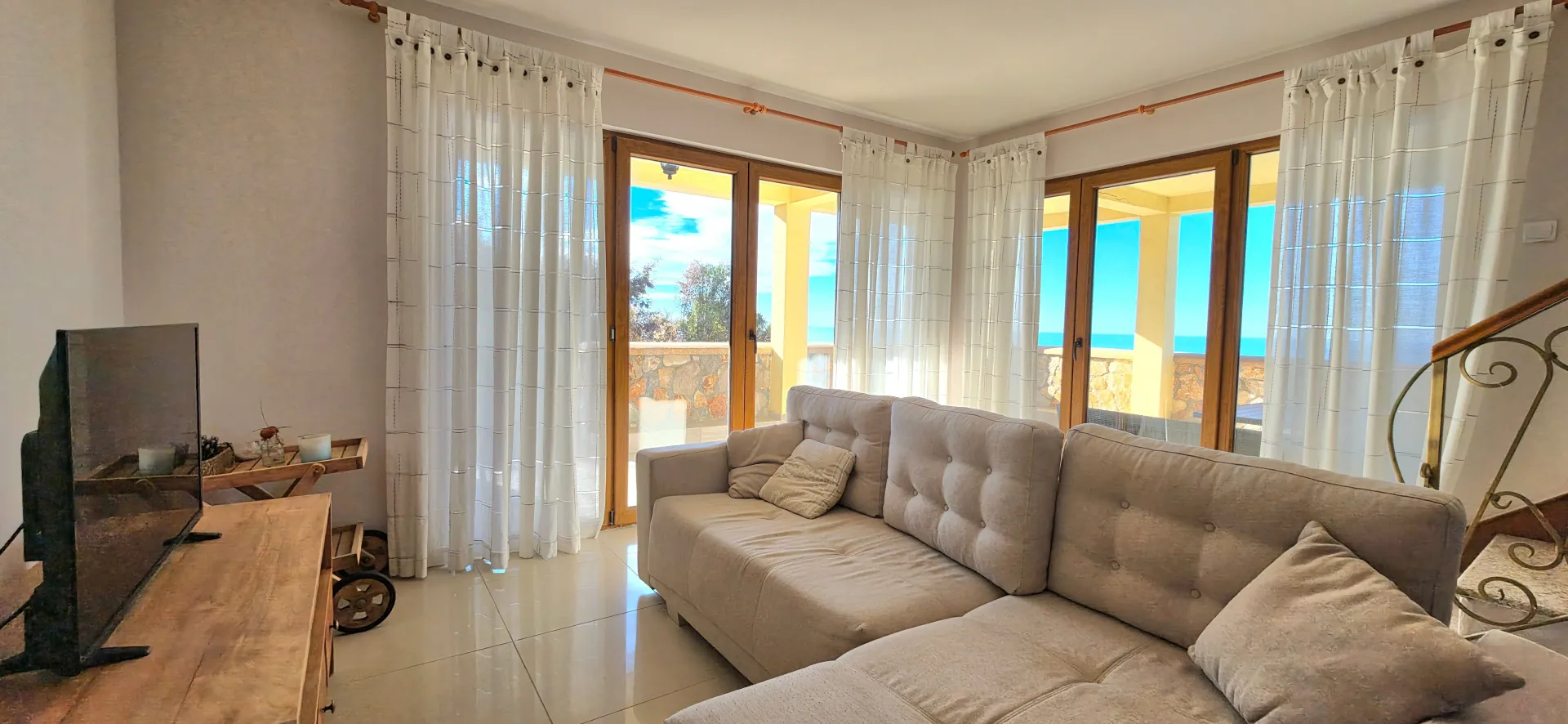 Bright living room with a sofa, TV, and access to a terrace with a sea view.