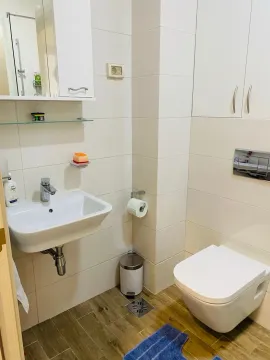 Manje kupatilo sa umivaonikom, ugradnim toaletom i bijelim pločicama. - image 12