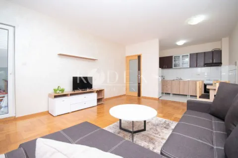 Living room with a sofa, TV unit and a view of the kitchen in the background. - image 3