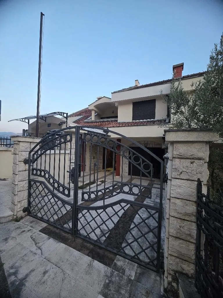 Exterior of a family house with a yard gate and paved courtyard.