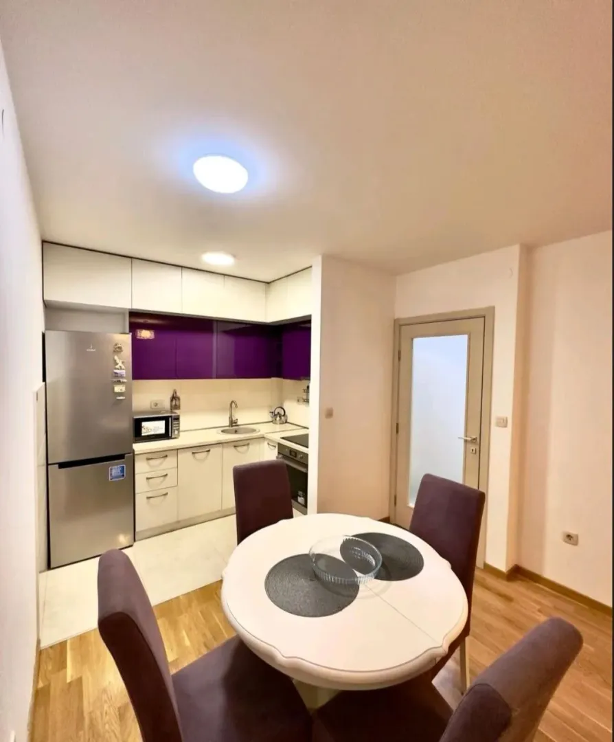Dining area with a view of a small kitchen with purple cabinets.