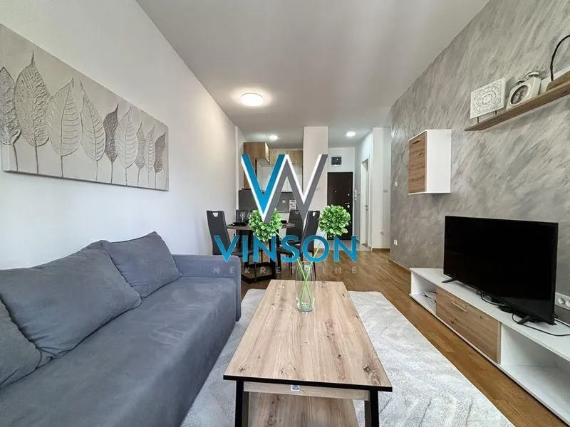 Living room with sofa, TV and dining area in the background.