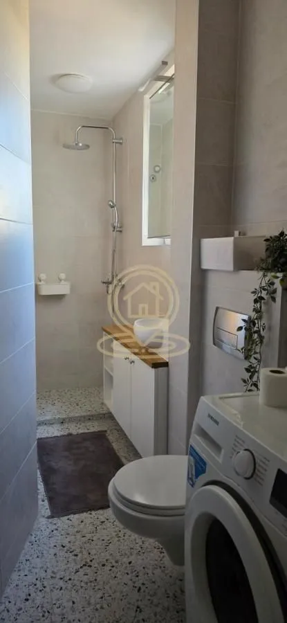 Moderno kupatilo sa tuš kabinom, umivaonikom i veš mašinom.