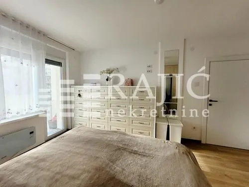 Furnished bedroom with a double bed, large chest of drawers, and balcony access.