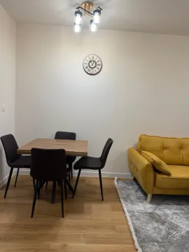 Trpezarijski sto sa stolicama pored žutog kauča u dnevnoj sobi. - image 3