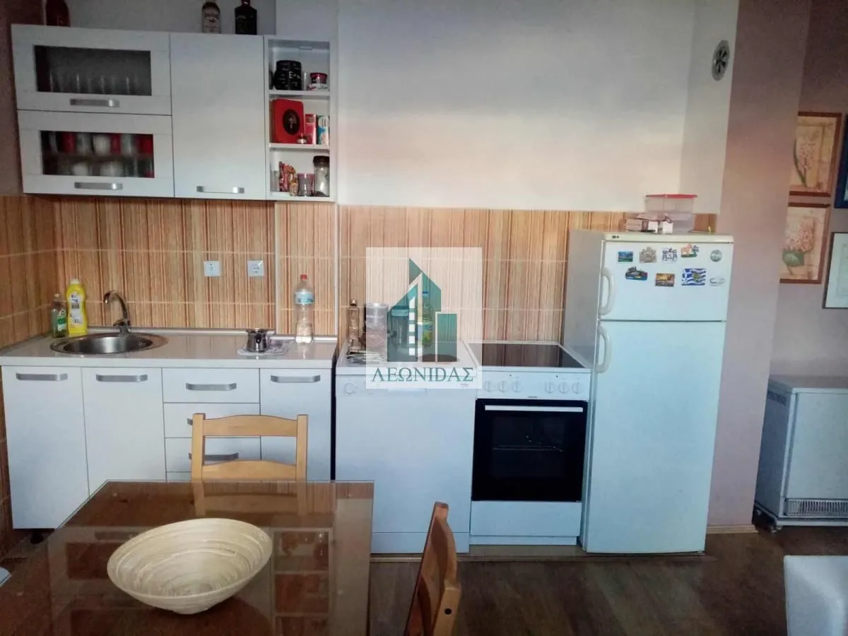 Small kitchen with white cabinets, stove, and refrigerator.