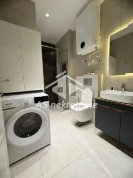 Modernly equipped bathroom with a washing machine, shower cabin, and built-in fixtures. - image 12