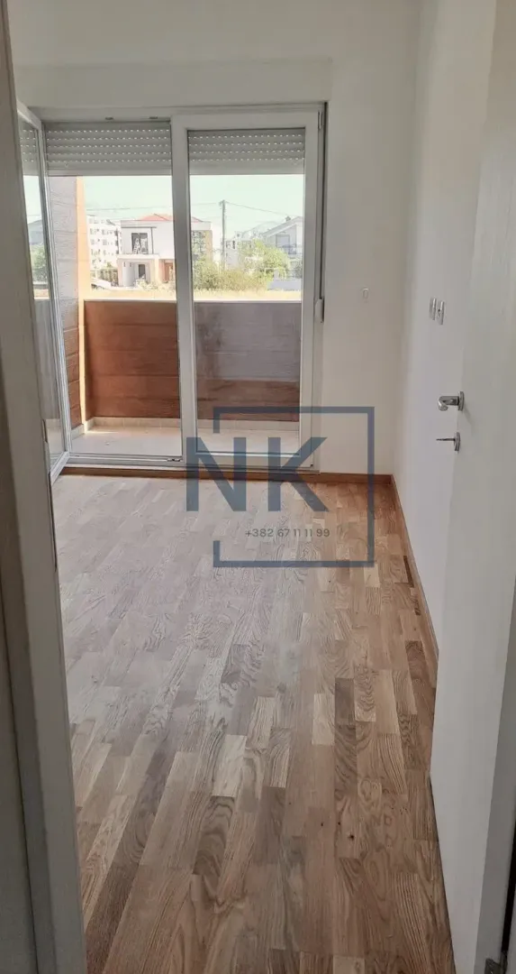 Empty room with hardwood flooring and access to a balcony.