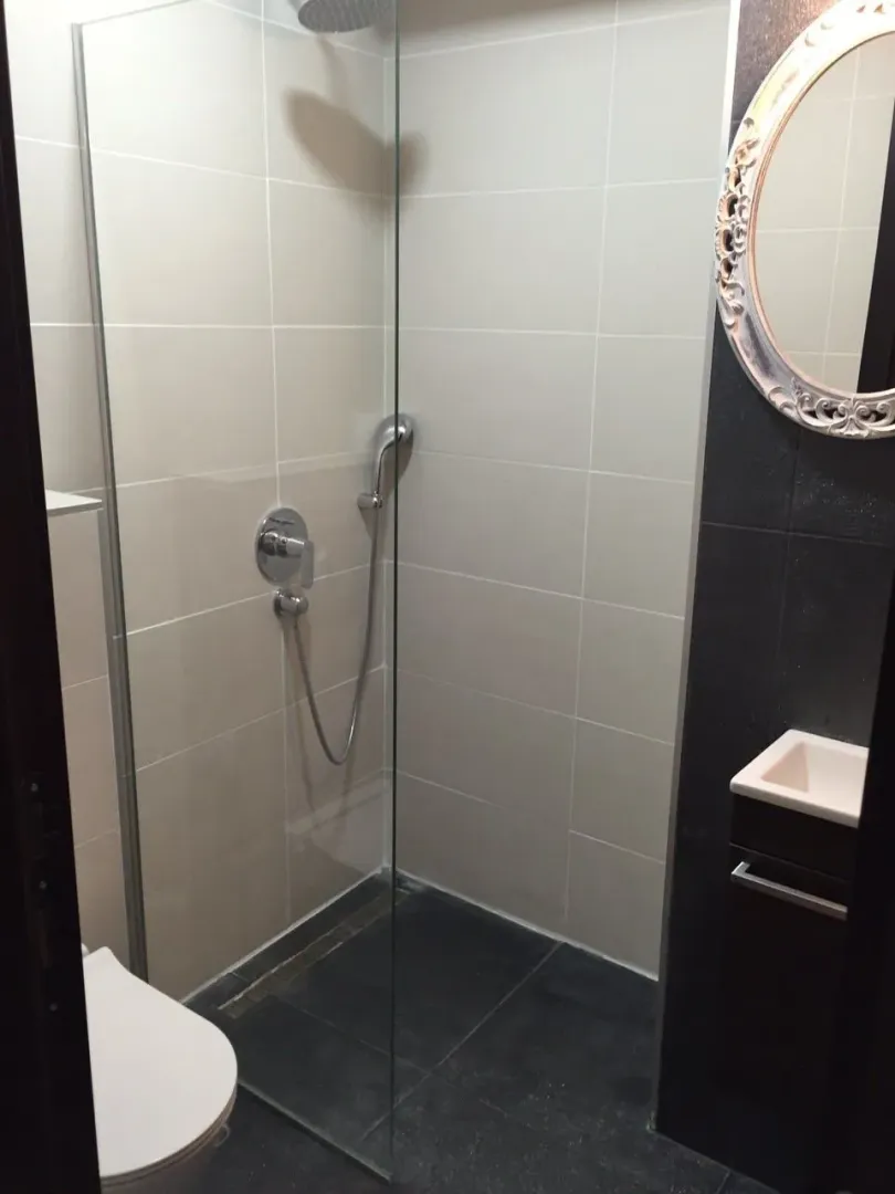 A modern bathroom featuring a glass walk-in shower and a decorative mirror.