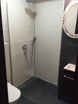 A modern bathroom featuring a glass walk-in shower and a decorative mirror. - image 8