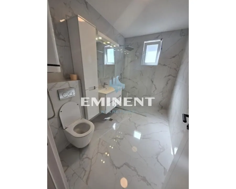 Modern equipped bathroom with a walk-in shower and marble tiles.